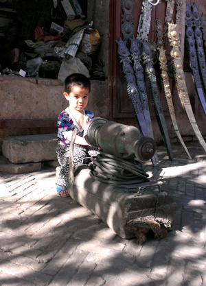 This perhaps 3 year-old boy is already learning from his father, a blacksmith.